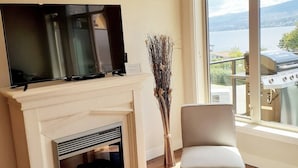 Ein Wohnzimmer mit Kamin, Fernseher und Seeblick.
