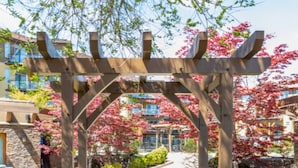 Ein Garten mit einem hölzernen Pergola-Anbau und einem Weg, der zu einem Gebäude führt.