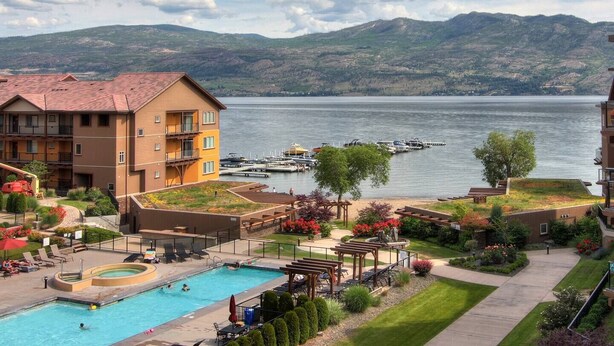 Ein Hotel mit Schwimmbad, Außenbereich zum Sitzen und Blick auf einen See mit Booten.