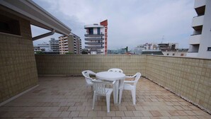 Une terrasse sur le toit, avec une table ronde et des chaises, un sol carrelé et une vue sur les bâtiments environnants.