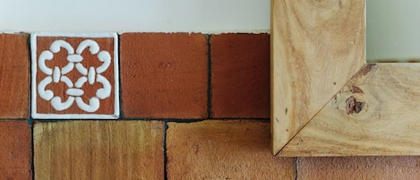 A corner of a room with a white wall, a decorative tile with a floral pattern, and a wooden floor.