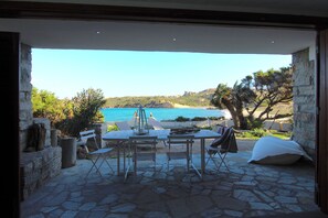 Un espace de restauration en plein air, avec une table et des chaises, offrant une vue sur une plage et la mer.