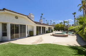 Une maison dotée d’un patio couvert, d’une piscine et de palmiers.