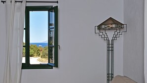 A room with a window offering a view of the sea, a floor lamp, and a sofa with red cushions. - Santa Maria Studio 5 Mins From the Beach (Paros)