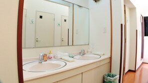 Un bagno con due lavandini, uno specchio grande e un cestino.