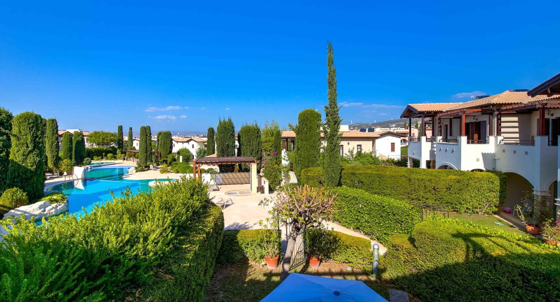 A resort with a swimming pool, manicured gardens, and Mediterranean-style villas.