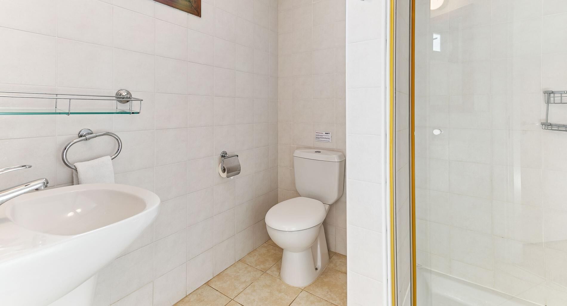 Un baño con lavamanos, inodoro y cabina de ducha de vidrio.