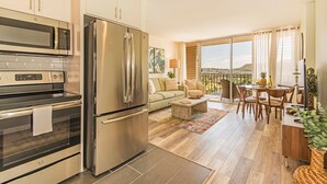 A modern kitchen with stainless steel appliances, a dining area with a view, and a balcony with a table and chairs. - Waikiki Moana Inn (Honolulu)