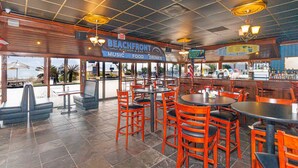 A restaurant with multiple tables and chairs, a bar area, and a view of the ocean. - Sand Dunes 2434 (Myrtle Beach)