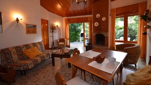 Un salon chaleureux avec un plafond en bois, un canapé, une table à manger et une cheminée.