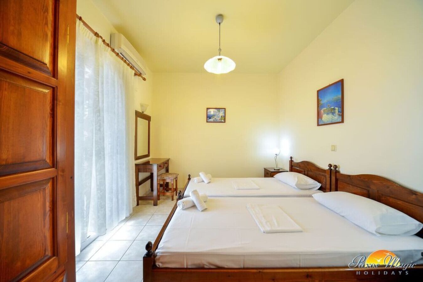 Une chambre d’hôtel avec deux lits, un bureau, une chaise et une fenêtre avec des rideaux.