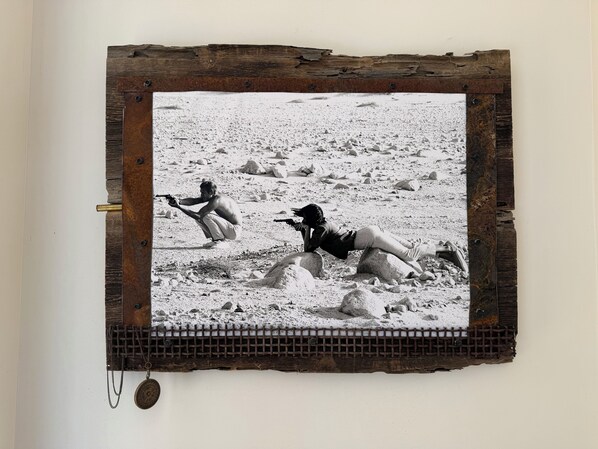 A framed photograph of two people in a desert setting, one holding a gun.