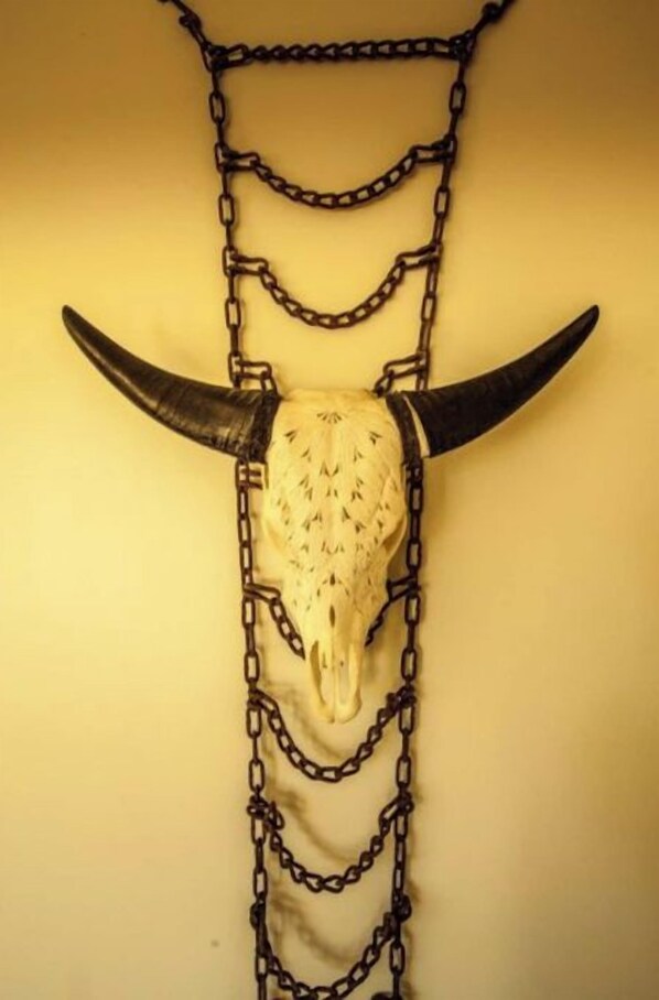 Een schedel met hoorns en kettingen hangend aan een muur.
