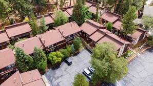 Un hotel a più piani con tetto in tegole rosse, immerso nel verde e con un parcheggio.