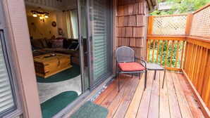 Un terrazzo in legno con una porta scorrevole in vetro che dà su un soggiorno con divano e un baule di legno.