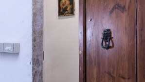 Eine Holztür mit einem Metallgriff, ein Lichtschalter an der Wand und ein gerahmtes Bild an der Nachbarwand.