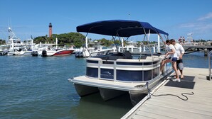 Un barco amarrado en un puerto deportivo, con un faro al fondo.