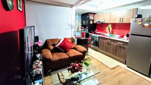 A modern kitchen with a brown sofa, a glass coffee table, and a red wall. - Complete Apartment in Coapa CDMX (Ciudad de México)