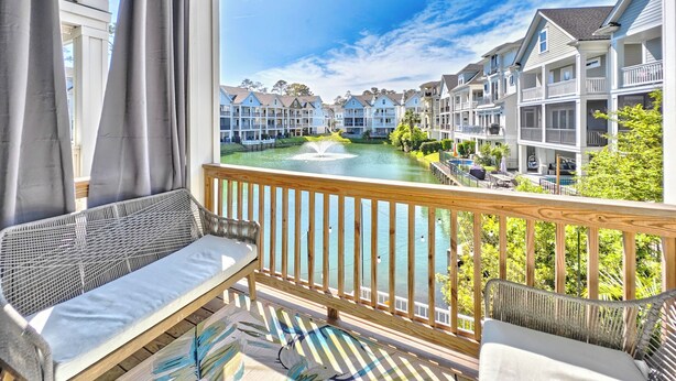 Ein Balkon mit Blick auf einen Fluss, mit Holzdeck und einer Sitzecke inklusive Sofa und Sessel.