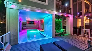 Ein Whirlpoolbereich mit Holzterrasse, einer Sitzecke mit Kissen und Lichterketten.