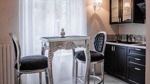 Une cuisine avec des meubles blancs, une table à manger avec des chaises et une fenêtre avec des rideaux.