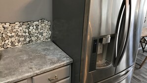 Un réfrigérateur en acier inoxydable doté d’un distributeur d’eau, d’un plan de travail en granit et d’un appareil à glaçons intégré.