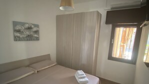 A bedroom with a bed, a wardrobe, a painting, and a window with blinds. - Villa Sole (San Pietro In Bevagna)