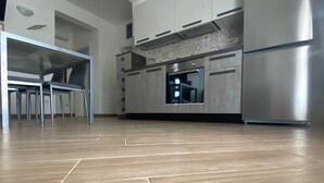 A modern kitchen with stainless steel appliances, a dining area with a glass table, and a patterned backsplash. - Villa Sole (San Pietro In Bevagna)