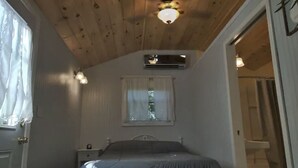 A bedroom with a bed, a ceiling fan, an air conditioning unit, a window with curtains, and a door. - Tiny House on the Farm: Watch Farm Animals, Near Buffalo River (Western Grove)