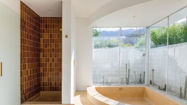 Une salle de bain moderne avec une baignoire sur pieds, une douche à parois de verre et une vue sur l’extérieur.