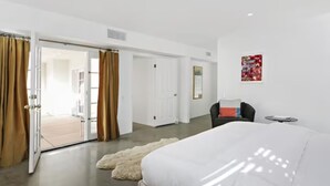 Une chambre d’hôtel moderne dotée d’un grand lit, d’un petit coin salon et d’une porte donnant sur un balcon.