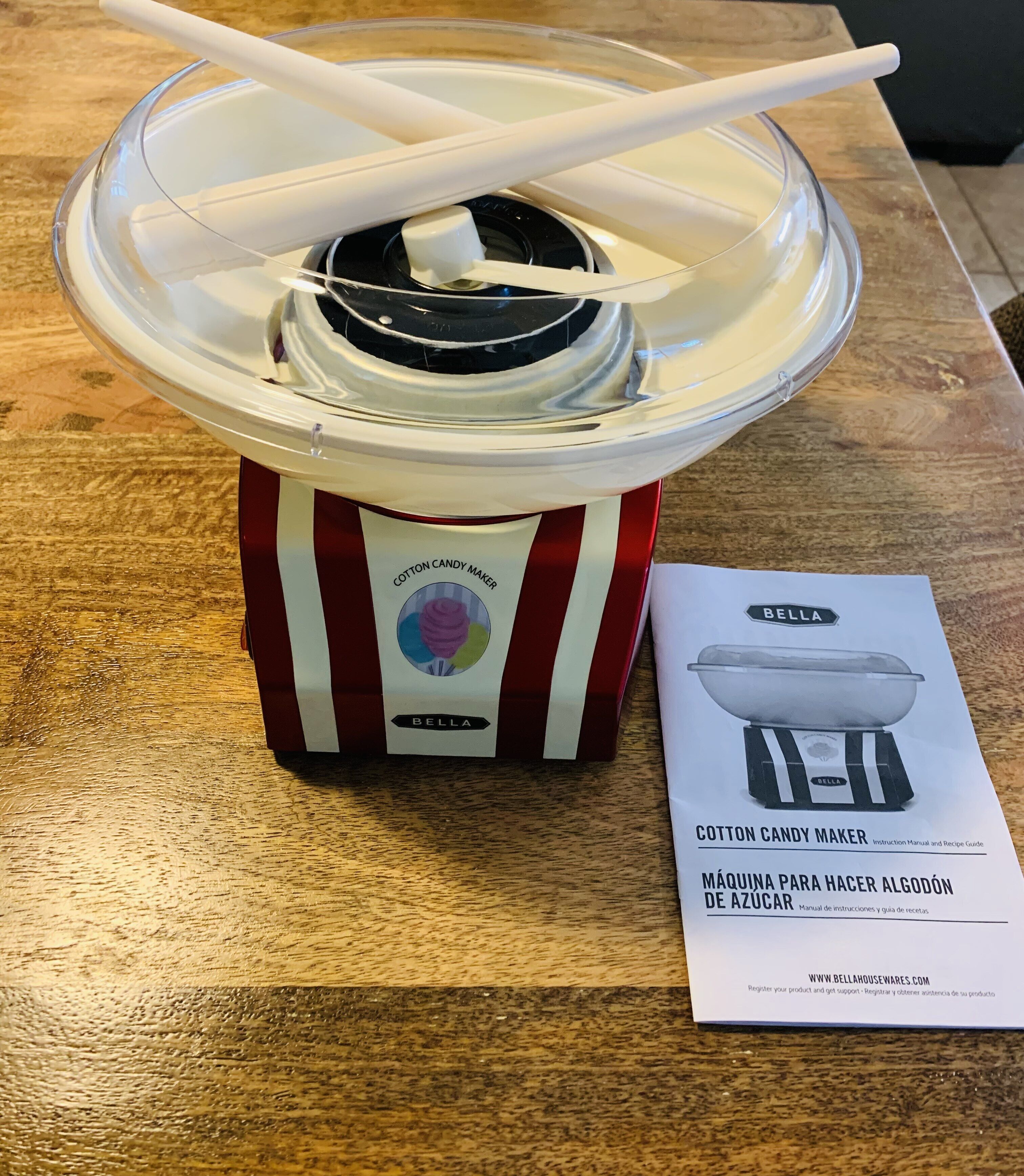 A cotton candy maker with a manual on a wooden table.