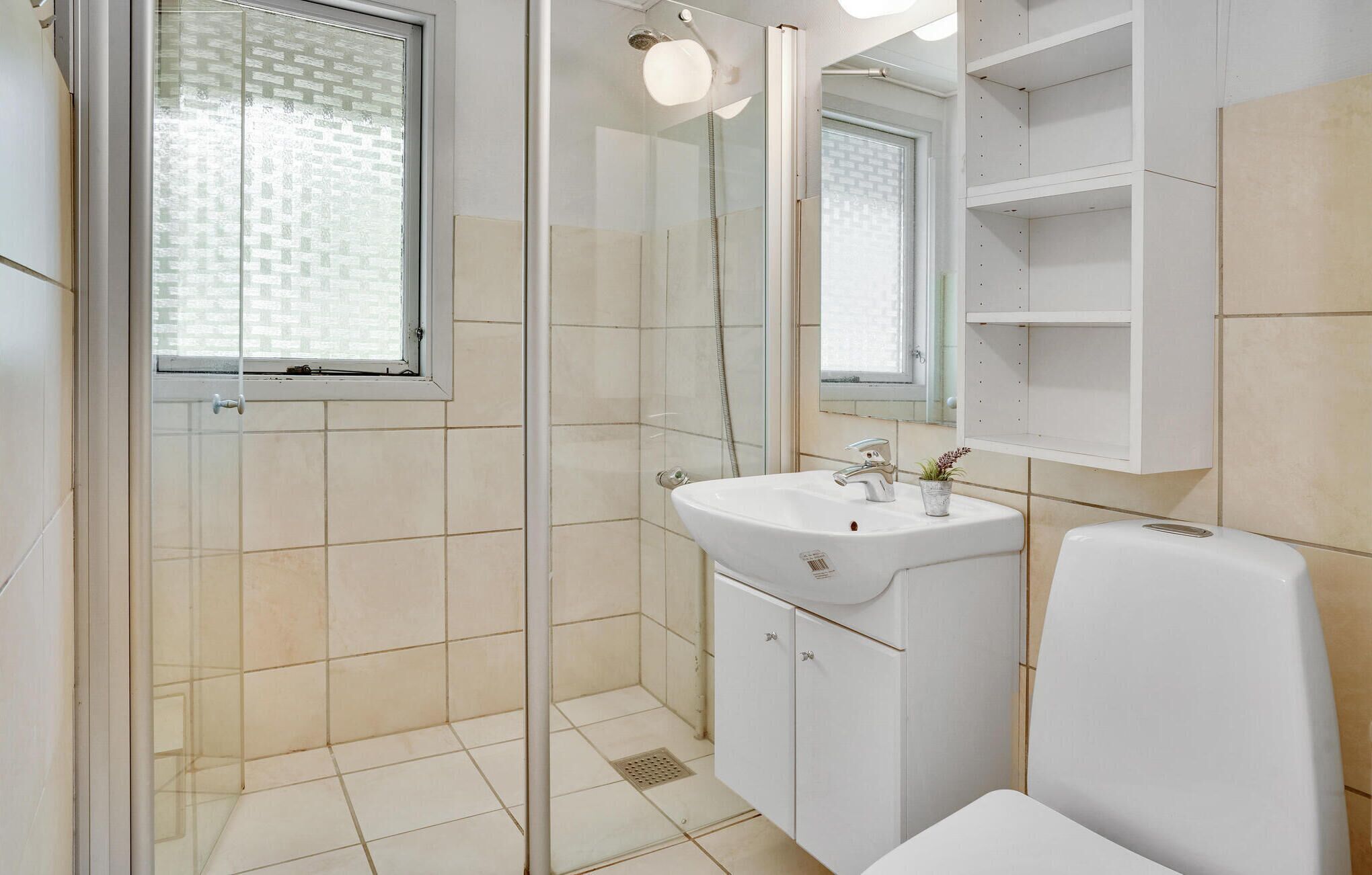 Ein modernes Badezimmer mit Duschkabine aus Glas, einem weißen Waschbecken und einer Toilette.