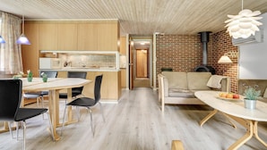 A modern kitchen with wooden cabinets, a dining area with a table and chairs, and a living area with a sofa and a small table. - 4 bedroom beautiful home in Hemmet (Hemmet)