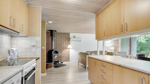 A modern kitchen with wooden cabinets, a built-in stove, and a brick wall. - 4 bedroom beautiful home in Hemmet (Hemmet)