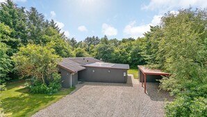 A modern building with a gravel driveway, surrounded by dense greenery and trees. - 4 bedroom beautiful home in Hemmet (Hemmet)