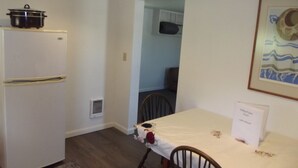 A compact kitchen with a refrigerator, a dining table with a floral tablecloth, and a framed picture on the wall. - Meadow Cabin (Meeker)