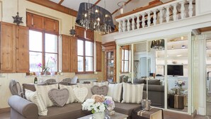 A cozy living room with a brown sofa, heart-shaped pillows, a coffee table with a vase of flowers, and a television in the background. - Winter Garden - NAVONA SQUARE (Roma)