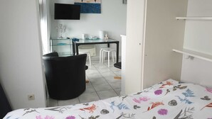 Een slaapkamer met een bed, een bureau en een stoel. Er hangt een schilderij aan de muur en er is een raam.