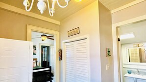 Un couloir avec un réfrigérateur blanc, un ventilateur de plafond et une porte donnant sur une salle de bain.