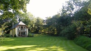 A house with a well-maintained lawn and a large tree in the foreground.