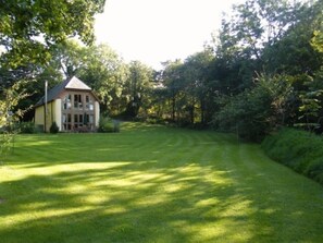 A house with a well-maintained lawn and a large tree in the foreground.