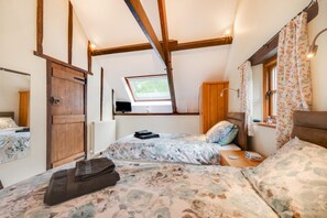 A cozy bedroom with two beds, a skylight, wooden beams, and a window with floral curtains. - 2 Bed in Meshaw (oc-meadow) (Meshaw)