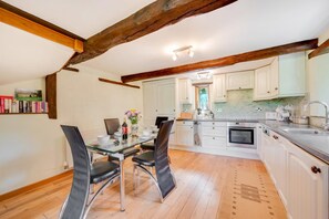 A modern kitchen with white cabinets, a dining table with chairs, and a large island with a sink. - 2 Bed in Meshaw (oc-meadow) (Meshaw)