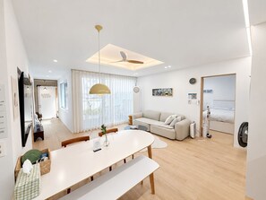 A modern living room with a sofa, dining table, and a ceiling fan. - 6Min Hongdae | 83㎡ Family House | Private Yard (서울)