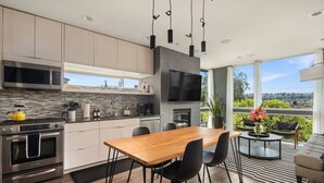 Une cuisine moderne avec une table à manger en bois, des chaises noires et un grand téléviseur.