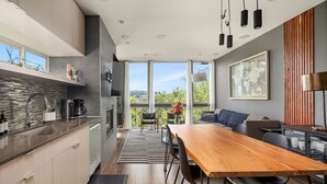 Une cuisine moderne avec un coin repas, de grandes fenêtres et une vue sur la verdure.