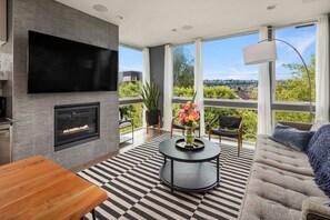 Ein modernes Wohnzimmer mit Kamin, Flachbildfernseher, rundem Couchtisch und einer Couch.
