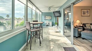 A spacious balcony with a dining area, a ceiling fan, a TV, and a view of the cityscape. - Walk to Beach: Resort-Style Siesta Key Condo! (Siesta Key)