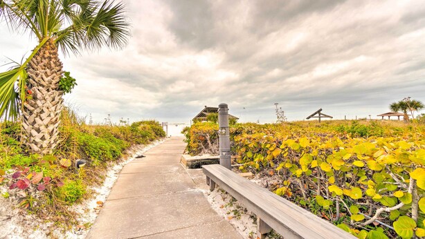 A pathway leading to a gazebo with a stone pillar, surrounded by lush greenery and a palm tree. - Walk to Beach: Resort-Style Siesta Key Condo! (Siesta Key)